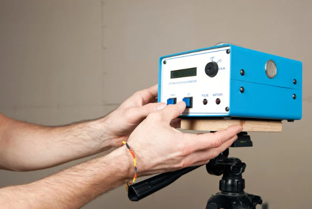 Technician setting up radon monitor during professional radon testing and mitigation service