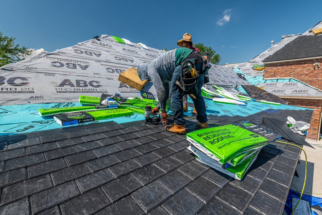 Contractor repairing asphalt shingles during professional roof tune-up service