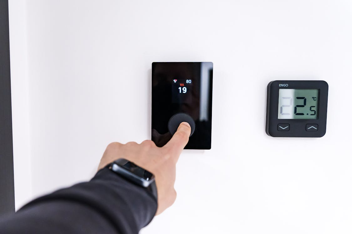 Adjusting digital thermostat during professional smart thermostat installation service