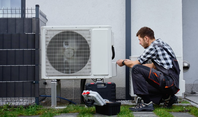 Technician performing annual HVAC maintenance on outdoor air conditioning unit